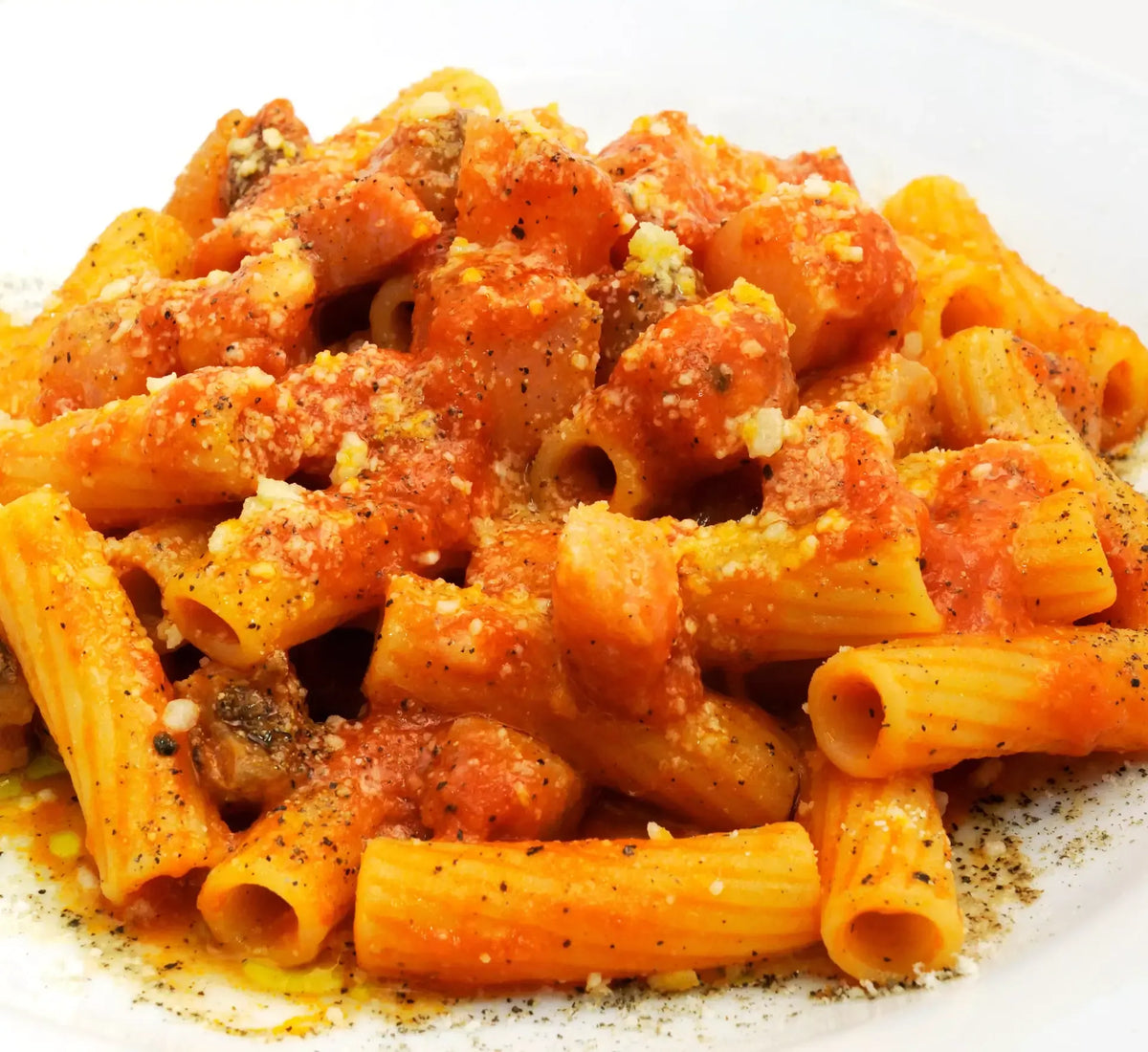 En indbydende tallerken pasta all'amatriciana med en fyldig rød sauce, gyldne stykker guanciale og et strejf af sort peber venter bare på at blive smagt.