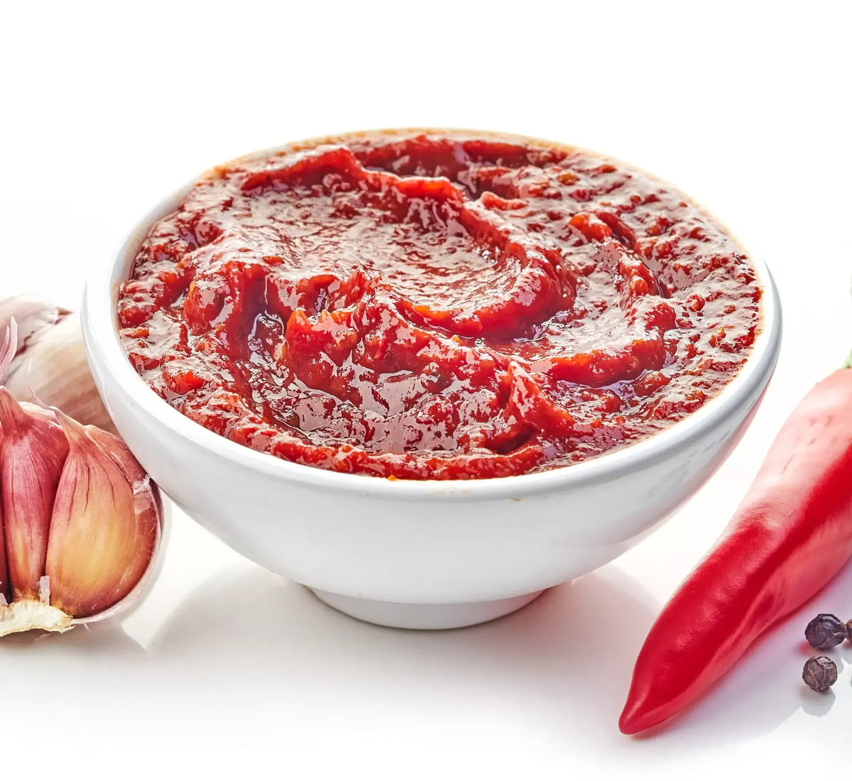 Un atractivo cuenco blanco que contiene una animada salsa Arrabbiata, enriquecida con guindillas picantes y ajo fresco, ideal para la pasta.