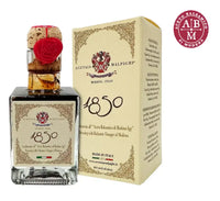 Una botella de vinagre balsámico tradicional de gran elegancia, presentada en una caja con adornos navideños, adornada con un sello rojo y refinados detalles.