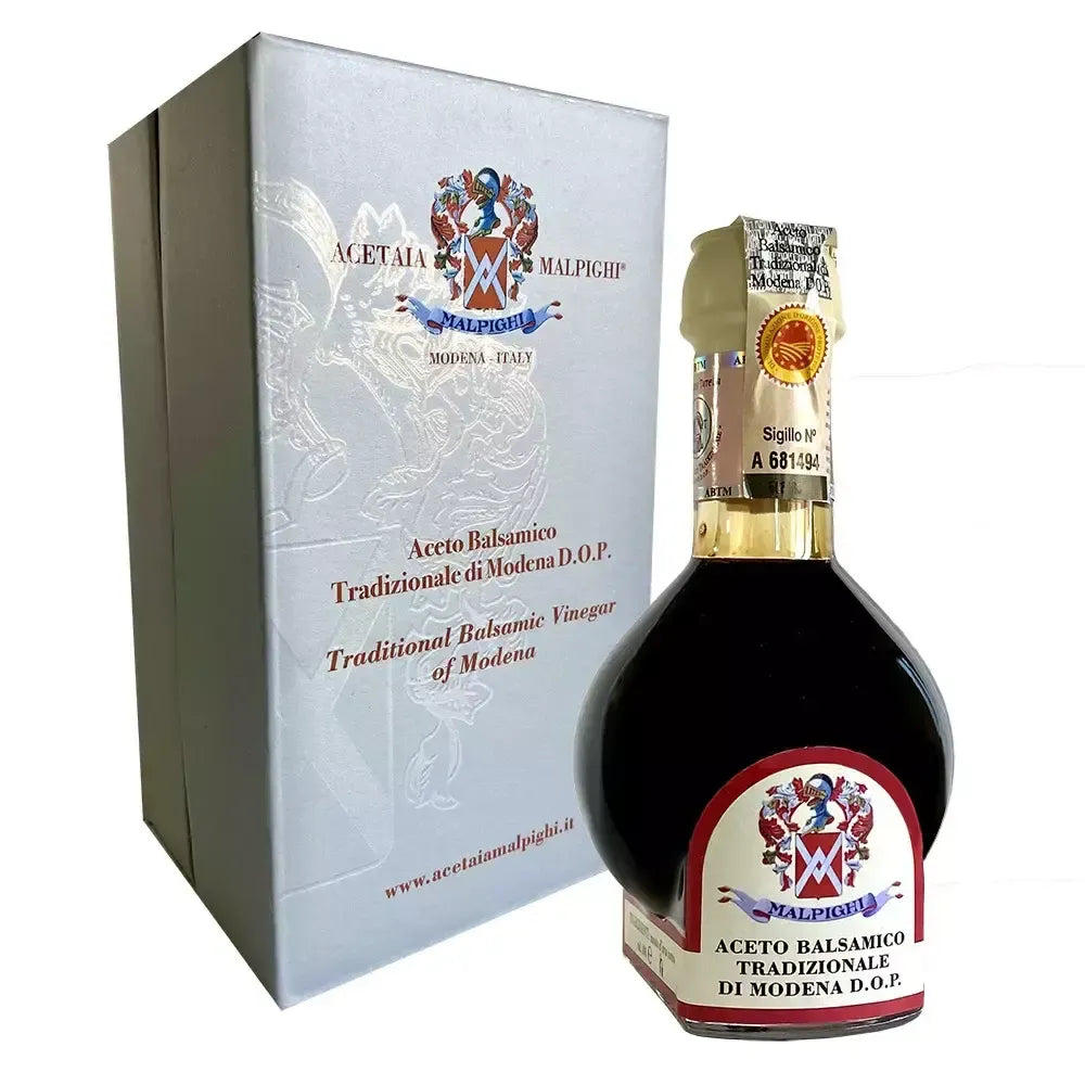 Una scatola raffinata contiene una bottiglia di Aceto Balsamico Tradizionale di Modena DOP, Affinato, con sigillo di prestigio.