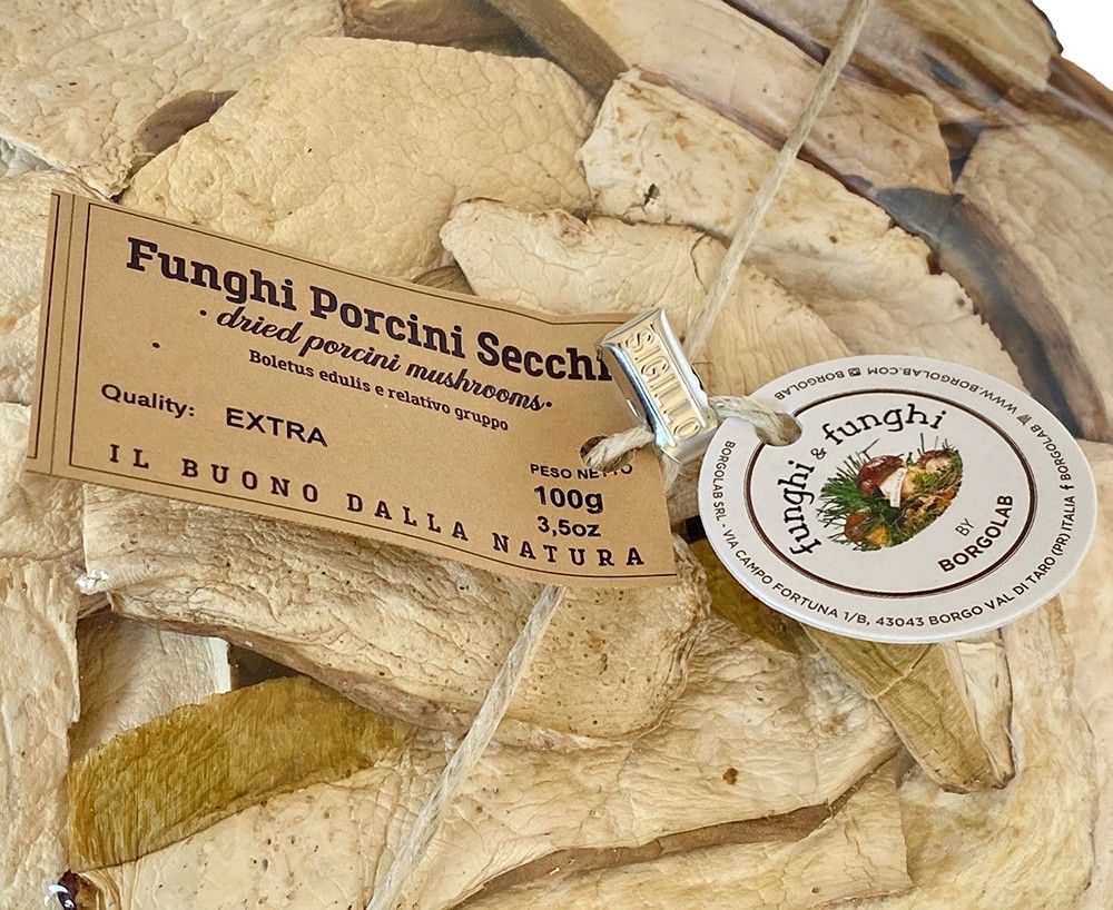 Un sacchetto di pregiati funghi porcini secchi di qualità extra, ciascuno con un'etichetta elegante, promette un assaggio di natura in ogni fetta croccante e profumata.