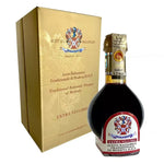 Una bottiglia sofisticata di Aceto Balsamico Tradizionale di Modena DOP, racchiusa in una confezione oro, rappresenta l'eccellenza secolare.