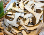 Un cesto rustico contiene Funghi Porcini finemente affettati, essiccati al sole e dal forte aroma di bosco, ideali per ricette gourmet.