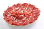 Delizioso affettato di prosciutto stagionato, disposto artisticamente a forma di rosa su un piatto, valorizzando i colori e i sapori autentici dell'Italia.