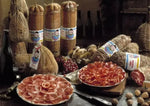 Metà di un fiocco di prosciutto stagionato per 9 mesi, con cotenna, elegantemente affettato su un tavolo rustico.
