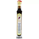 Una bottiglia dello Stravecchio Gocce d'Oro, condimento balsamico, con sigillo rosso e etichetta di lusso, di tonalità ricca ed elegante.