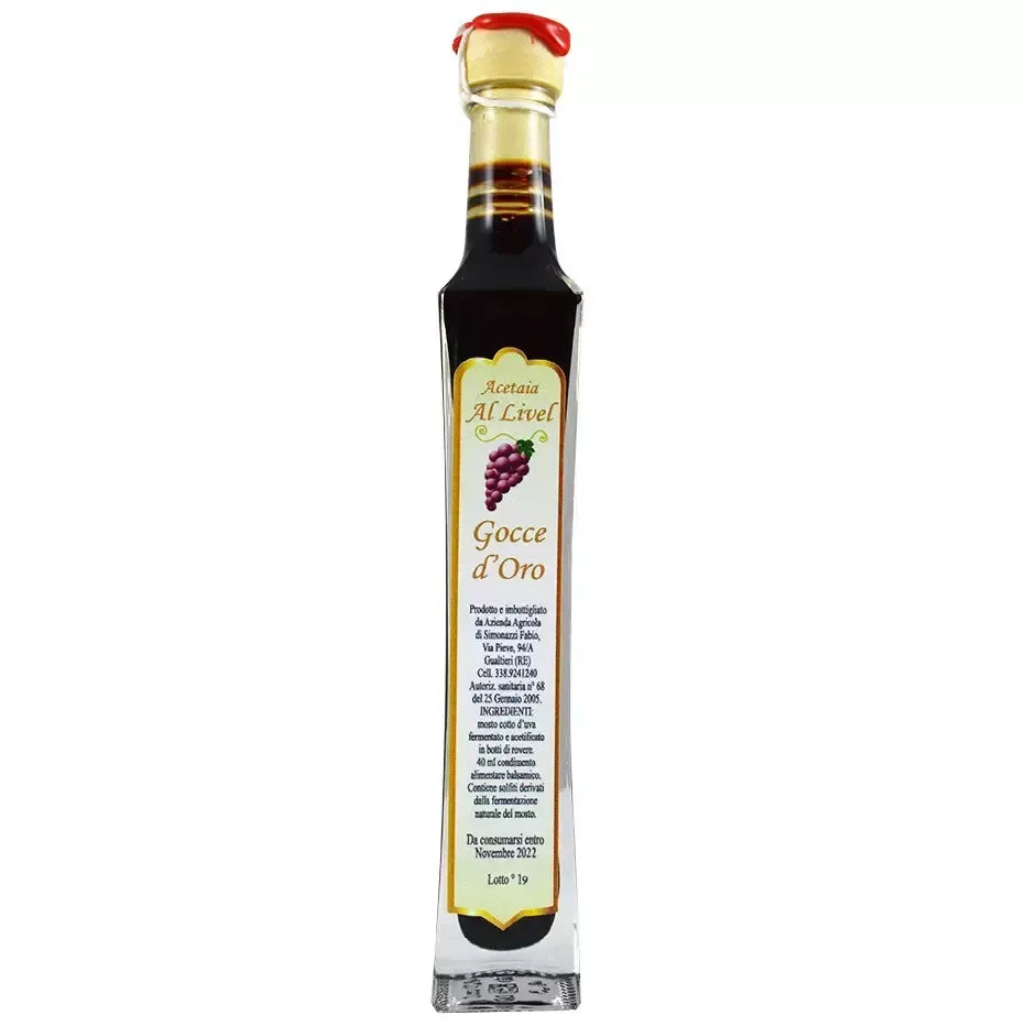 Una bottiglia dello Stravecchio Gocce d'Oro, condimento balsamico, con sigillo rosso e etichetta di lusso, di tonalità ricca ed elegante.