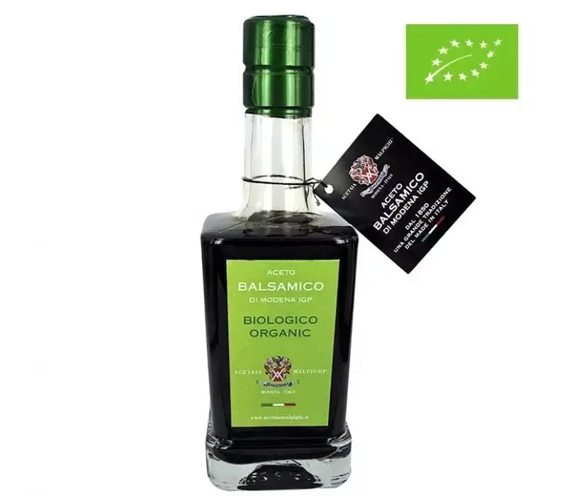 Eine Flasche biologischer Aceto Balsamico di Modena IGP, gekennzeichnet durch ein grünes Etikett, einen grünen Verschluss und das europäische Bio-Emblem.