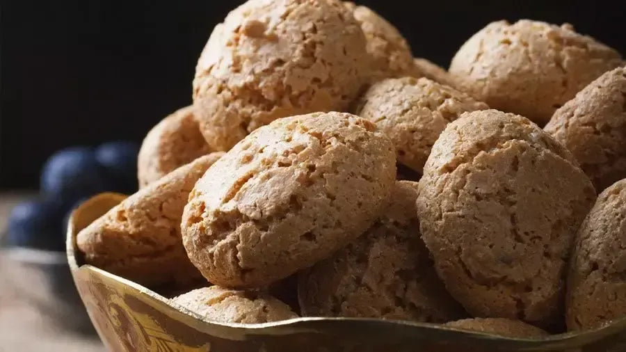 Primo piano su Amaretti Chiostro di Saronno: croccanti, dorati, friabili, posati su uno sfondo rustico che evoca tradizione.