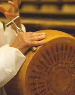 Un esperto casaro è intento a ispezionare la crosta di un formaggio Parmigiano Reggiano Vacche Rosse stagionato 24 mesi, ancora nella sua forma intera.