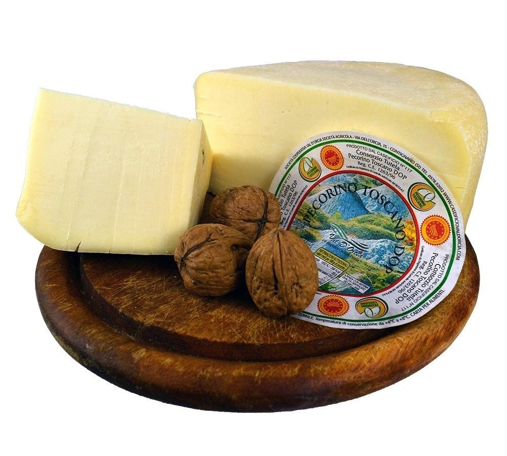 En hel färsk Pecorino Toscano DOP, placerad på en träskärbräda, åtföljd av valnötter, med synlig etikett, redo att avnjutas.
