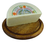 Uno splendido tagliere di legno ospita una metà di Pecorino Toscano DOP fresco, di colore bianco, con un'etichetta colorata.