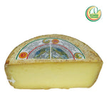 Un pezzo di Pecorino Toscano DOP, dal colore dorato e giallo, con il logo ben visibile, all'interno di un cesto regalo natalizio tipico italiano.