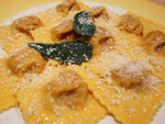 Deliziosi tortelli artigianali di zucca all'uovo, arricchiti da burro fuso e salvia fresca, con un tocco finale di parmigiano.