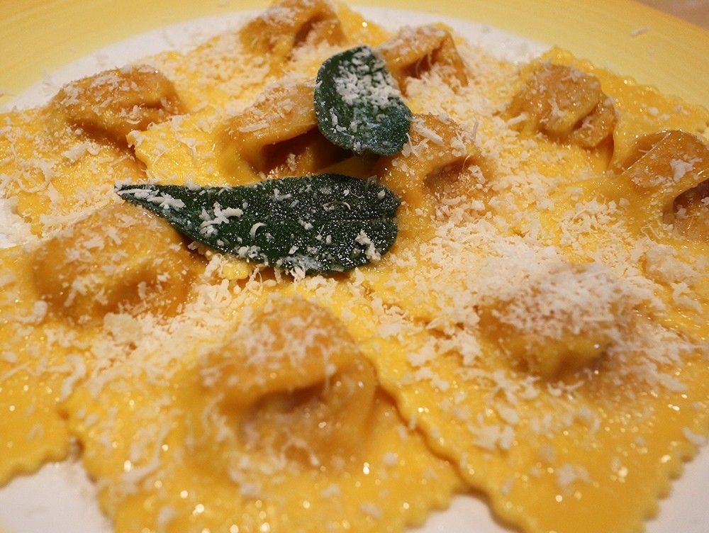 Deliziosi tortelli artigianali di zucca all'uovo, arricchiti da burro fuso e salvia fresca, con un tocco finale di parmigiano.