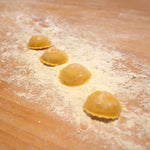 Deliziosi anolini artigianali all'uovo, riposano su una spianatoia infarinata, ripieni di autentico Parmigiano Reggiano DOP. Autentica pasta fresca tradizionale.