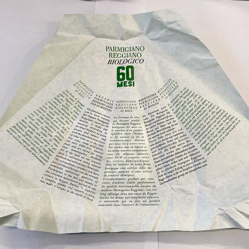 Visualizza un'immagine di Parmigiano Reggiano biologico stagionato 60 mesi, con enfasi sui suoi ricchi dettagli storici e qualità artigianale.