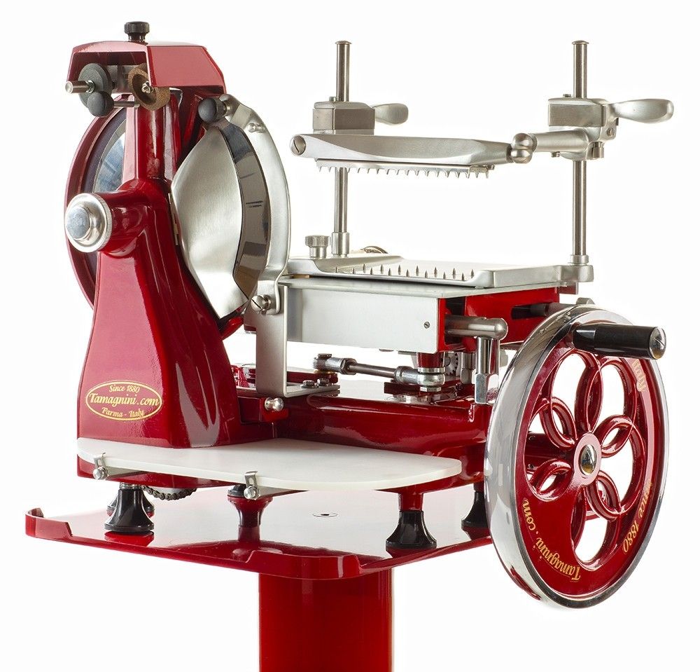 Un'elegante affettatrice manuale, dal volano rosso in stile vintage, dotata di lama in acciaio, perfetta per effettuare tagli precisi nelle deliziose prelibatezze di una salumeria gourmet.