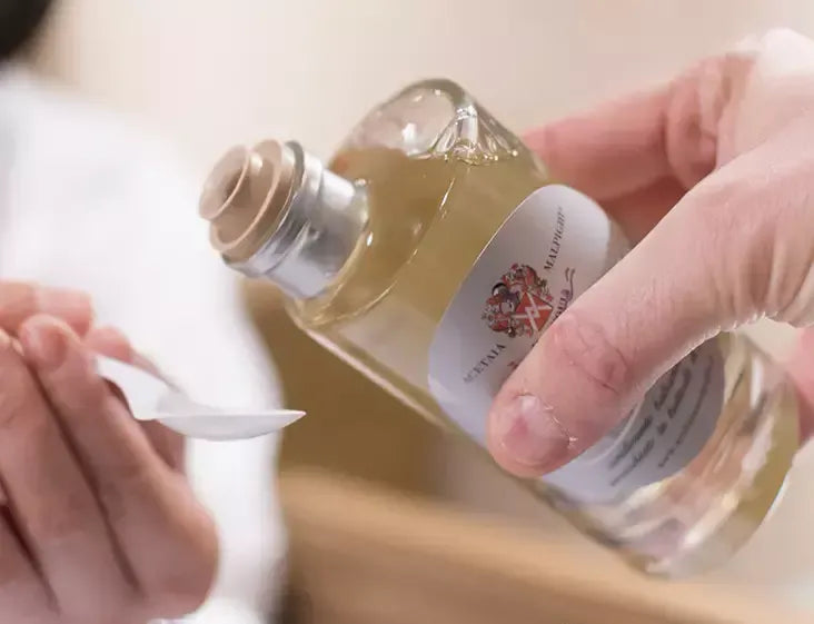 Mani esperte versano un condimento bianco di qualità, maturato per 5 anni, in un cucchiaio, evocando la tradizione e un sapore distinto.