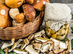 Un cesto di eccellenti funghi porcini secchi affiancato da un barattolo di porcini freschi, entrambi sprigionano un intenso aroma boschivo.