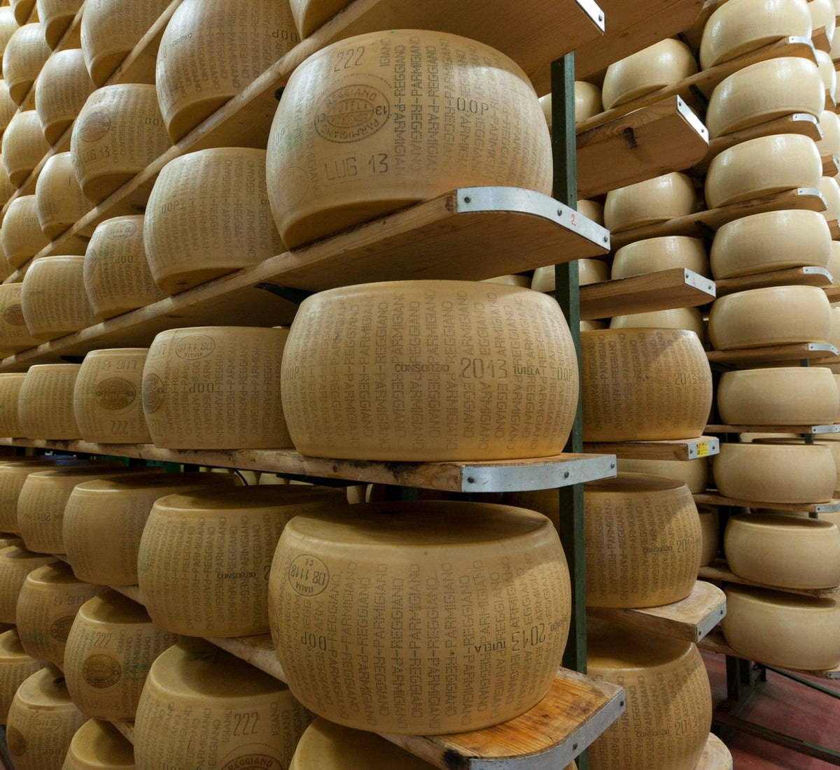 Parmigiano Reggiano Solodibruna van 24 maanden oud, gestapeld in de kelder, met een gouden korst en het DOP-logo duidelijk zichtbaar.