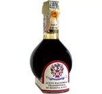Un'affinata bottiglia di Aceto Balsamico Tradizionale di Modena DOP, avvolta in vetro scuro con un'etichetta elegante e un sigillo dorato.