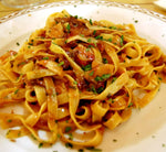 Un piatto di tagliatelle fumanti pronte per deliziare il palato, guarnite con sugo di funghi porcini e prezzemolo fresco.