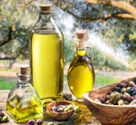 Guasco, olio d'oliva di qualità, presentato in bottiglie in un contesto naturale, arricchito da olive appena raccolte e alberi in lontananza.