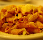Deliziose penne biologiche cotte al dente, condite con un ricco sugo di pomodoro e formaggio: la cena ideale per un pasto saporito e sano.