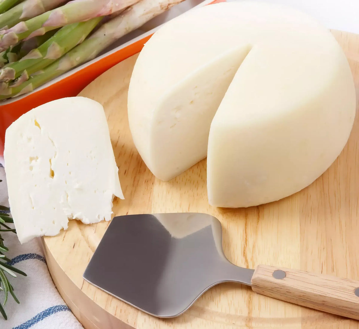 Geniet van de authenticiteit van de biologische Caciotta di Urzano, een romige bergkaas, gepresenteerd op een plank met verse asperges.