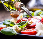 Una lattina di olio extra vergine d'oliva che si riversa su pomodori freschi e basilico, esaltando la vivacità e i sapori del Mediterraneo.