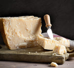 Un formaggio stagionato affettato è presentato su un tagliere di legno, con un coltello a fianco, esibendo la sua rusticità e texture, ideale per i gourmet.