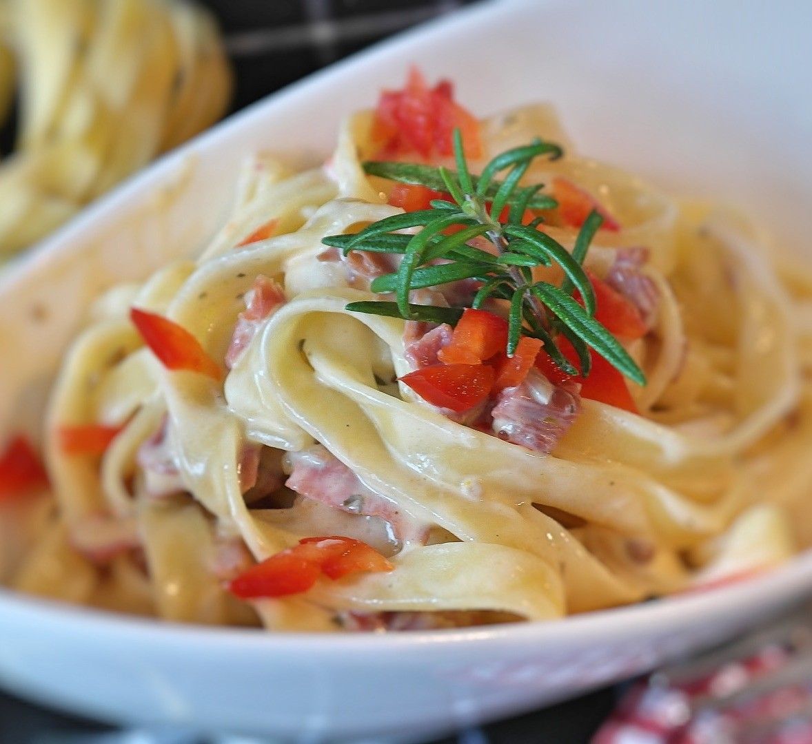 Deilige økologiske eggpappardelle, pyntet med en kremet saus og friske tomater, med en siste touch av rosmarin.