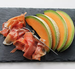 Una raffinata presentazione di Prosciutto di Parma DOP, stagionato 16 mesi e affettato finemente, abbinato a fette di melone fresco, il tutto su un piatto di ardesia.