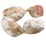 Deliziosi bocconcini di salame artigianale, presentati su uno sfondo bianco. Arricchiti con spezie aromatiche, mostrano una texture ricca ed allettante.