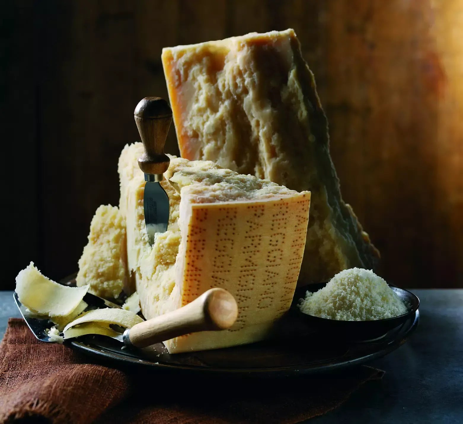 Scaglie di Parmigiano Reggiano stagionato 36 mesi, appoggiate su un tagliere rustico, che rimandano alle montagne italiane e ai loro sapori intensi. Autenticità e artigianalità ne sono l'essenza.