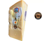 Un pregiato formaggio Parmigiano Reggiano, stagionato per 36 mesi, splendidamente confezionato per le festività natalizie, con etichette che testimoniano la sua qualità e premi vinti.