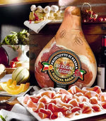 Un trancio di Prosciutto di Parma DOP, stagionato per 30 mesi, presentato su un tagliere rustico, accompagnato da frutta fresca e una bottiglia di vino.