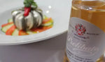 Un condimento bianco Prelibato Riserva di 8 anni, in una bottiglia, posizionato accanto a un piatto gourmet colorato che esprime l'eleganza culinaria italiana.