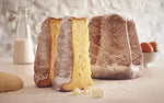 Un'invitante fetta di pandoro dorato e soffice, cosparsa di zucchero a velo, posata in un ambiente domestico, evoca l'intima atmosfera del Natale.