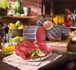 Metà di una bresaola di manzo Punt'Anca, posta su una tavola rustica, abbellita da agrumi e olio, ideale per un sofisticato antipasto.