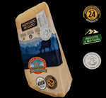 Rinomato formaggio italiano Parmigiano Reggiano DOP, stagionato per 24 mesi, presentato con etichette e su uno sfondo montano di colore blu.