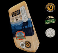 Rinomato formaggio italiano Parmigiano Reggiano DOP, stagionato per 24 mesi, presentato con etichette e su uno sfondo montano di colore blu.
