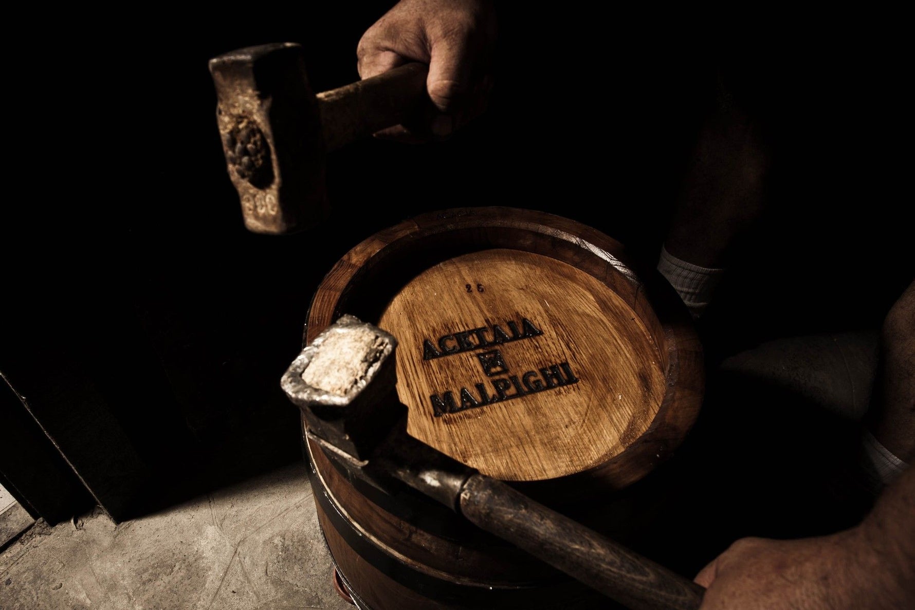 Artigiani esperti lavorano con cura una botte di autentico aceto balsamico di Modena DOP, esprimendo artigianalità e tradizione.
