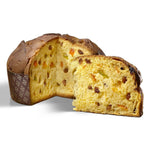 Un panettone tagliato rivela il suo interno soffice, ricco di uvetta e canditi, presentato in una carta decorativa.