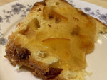 Una fetta di Panettone Tradizionale, dorata e con scorze candite, è presentata su un piatto decorato. Ideale per le feste, è realizzato a mano.