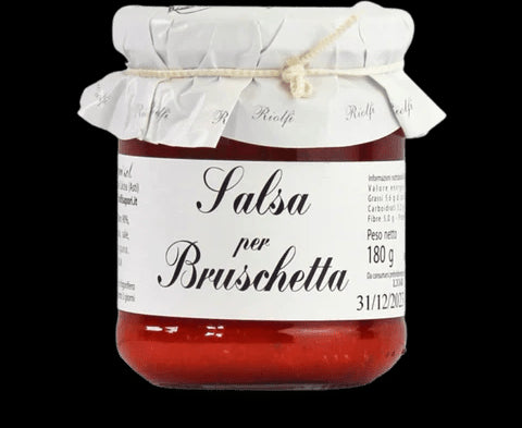 Valentino ofrece un tarro de salsa bruschetta, envuelto en una funda de papel atada con un cordel, con una etiqueta blanca.