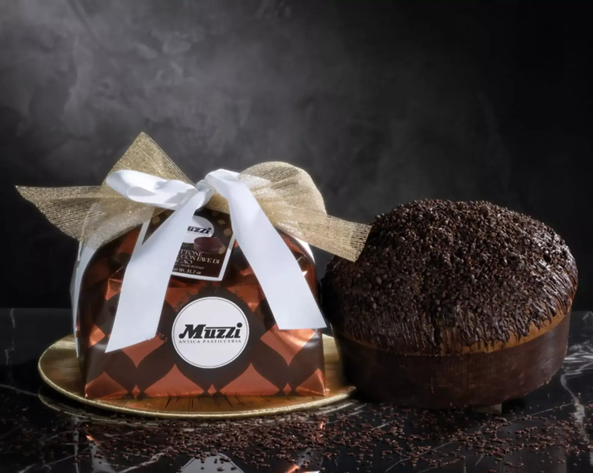 Un panettone artigianale, avvolto a mano, si distingue per l'aggiunta di cioccolato e fave di cacao, su un sofisticato sfondo.