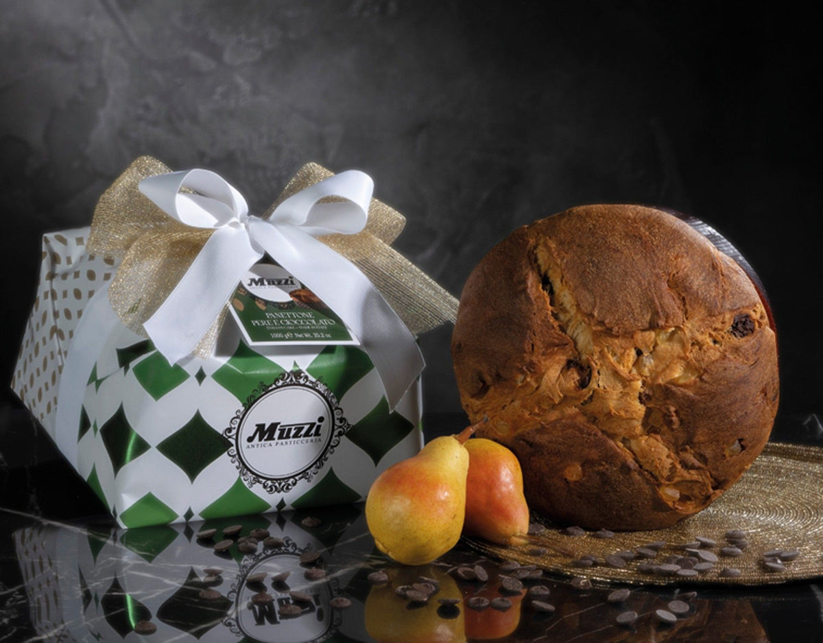 En panettone med päron och choklad, varsamt inslagen för hand, prydd med ett elegant band. Bredvid kompletteras den av färska päron och chokladflis.