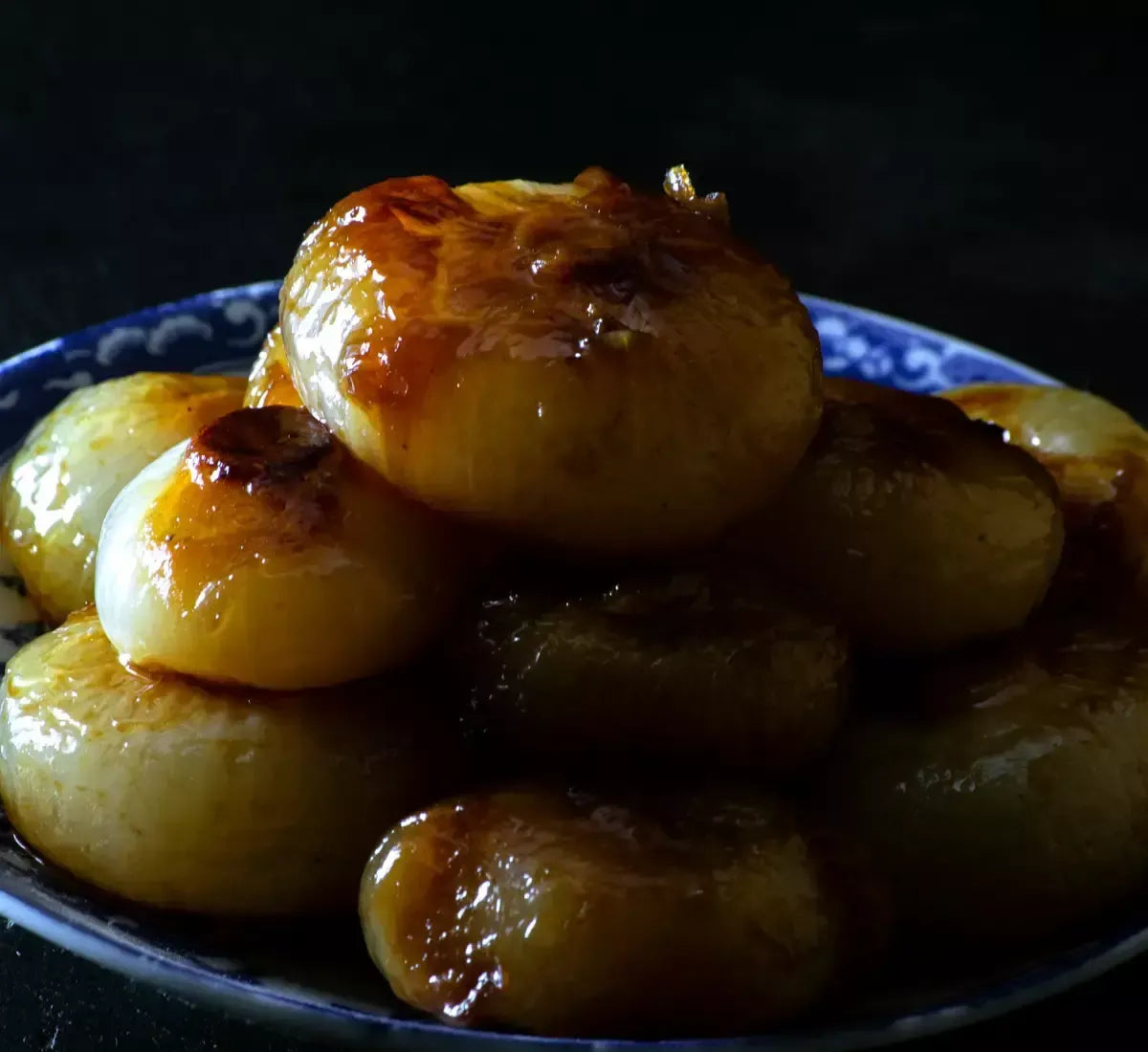 Köstliche Borettane-Zwiebeln, in Balsamico-Essig karamellisiert, sorgfältig auf einem blauen Teller angerichtet, mit authentischem, handwerklichem Geschmack.